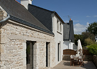 Chaumière en location dans le morbihan : vue du salon, avec pierres apparantes, cheminée, mobilier sympa pour ce gite de charme